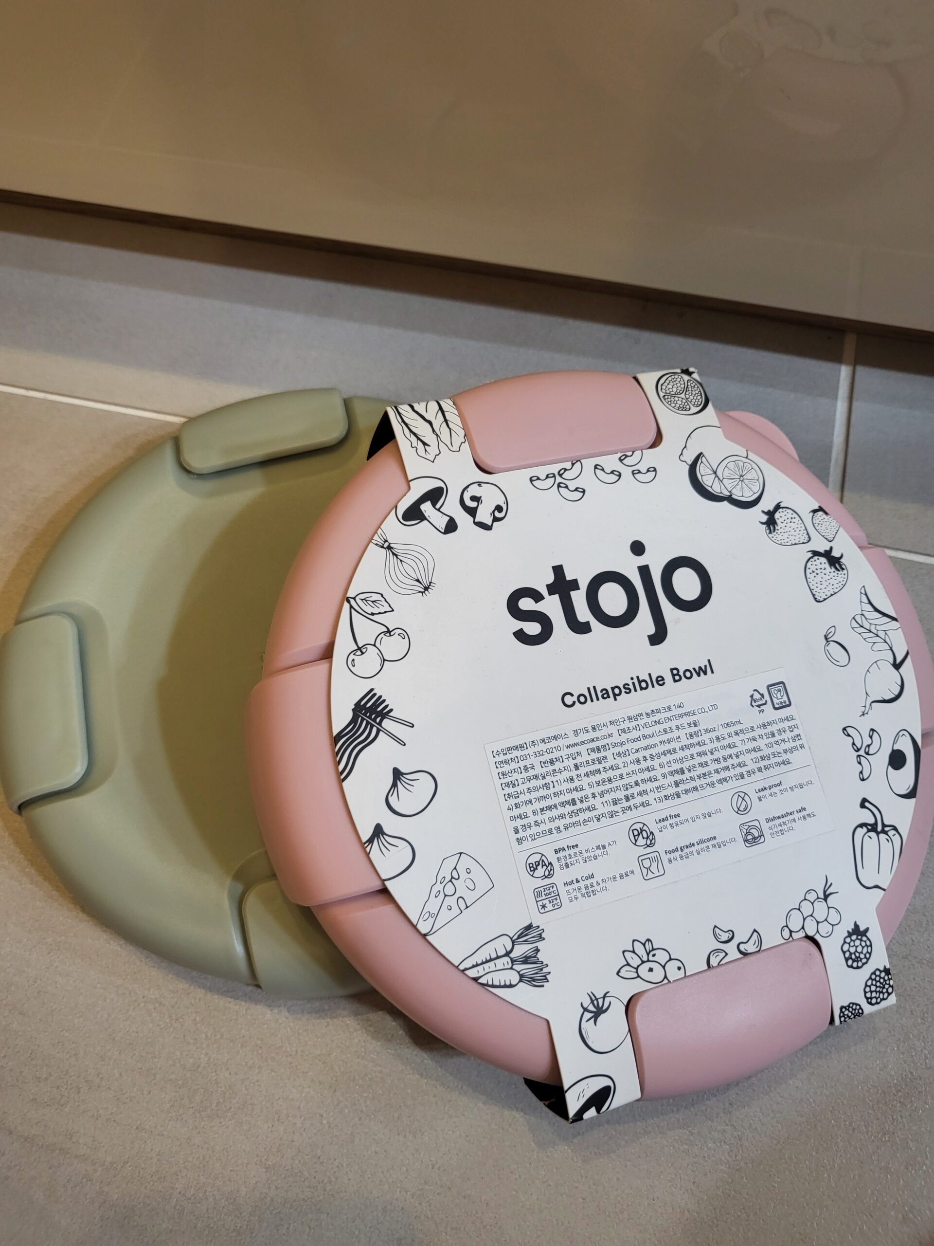 The two Stojo Collapsible Bowls, found at No No Shop in pink and sage green, stacked and folded down flat